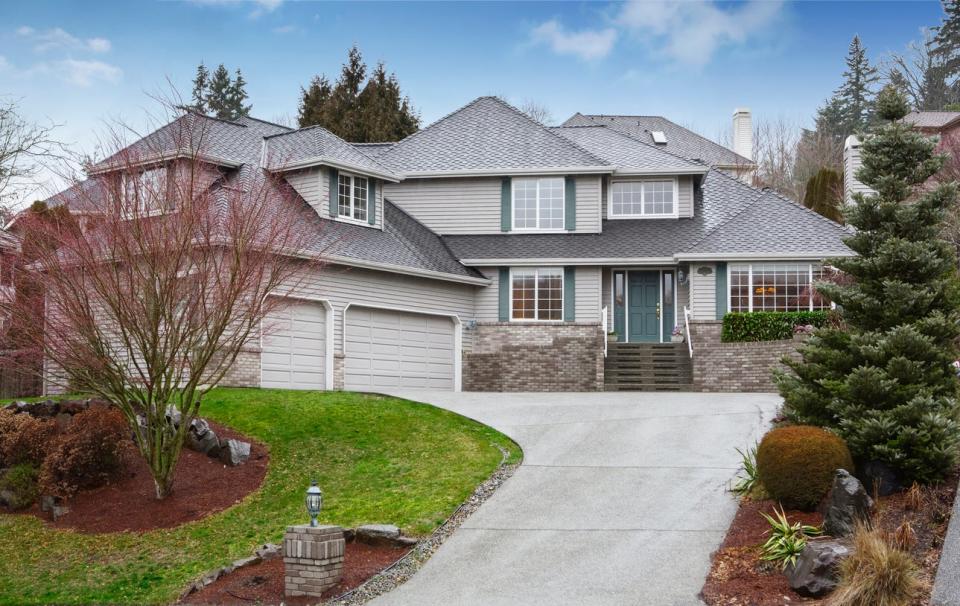 large house with sloped driveway and curved landscaping 