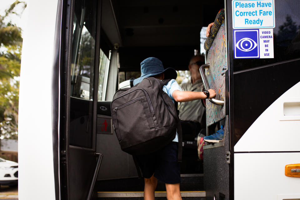 Australian schoolboy boards the bus for his school commute.