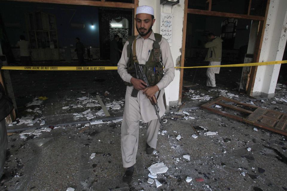 A security guard walks amidst debris after an explosion in a Shi'ite mosque in Peshawar