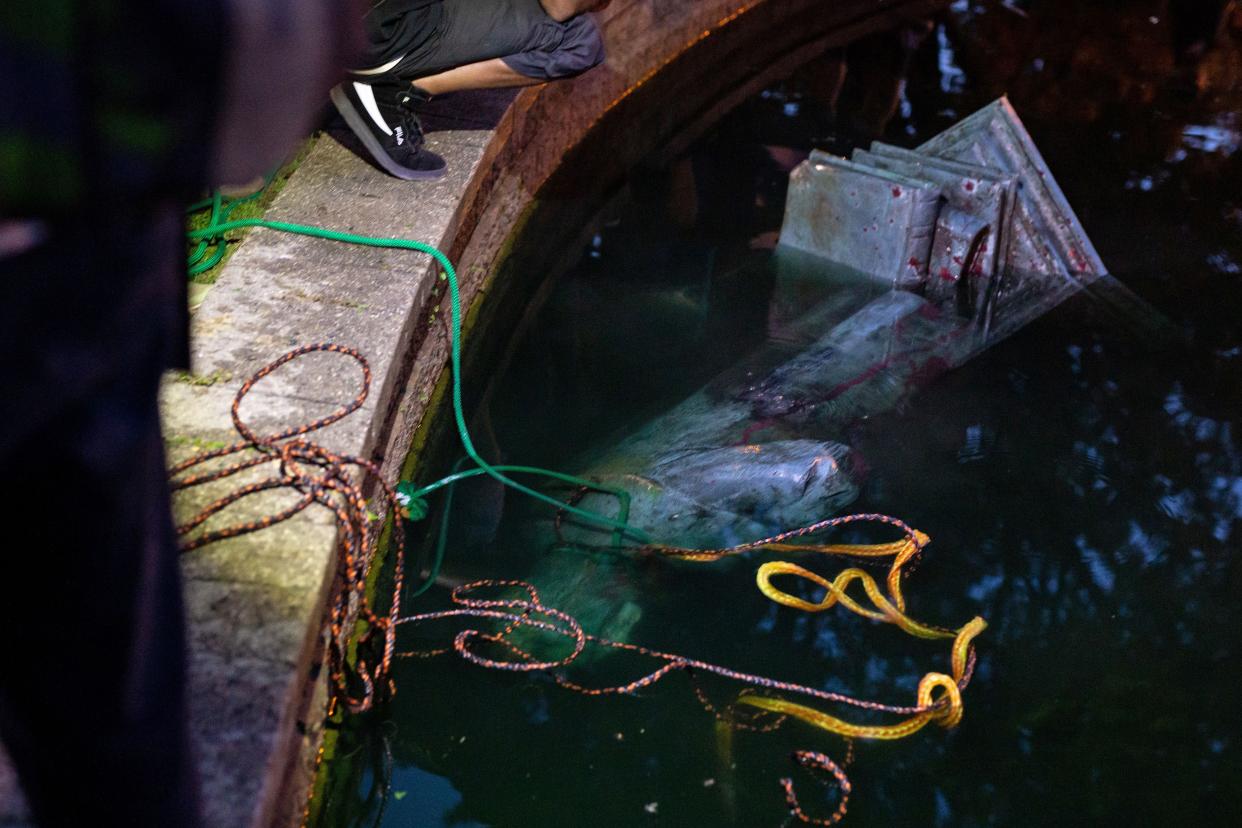 A statue of Christopher Columbus rests in a shallow pond after protesters pulled it off its pedestal and dragged it across a street in Richmond, Va. on June 9, 2020.