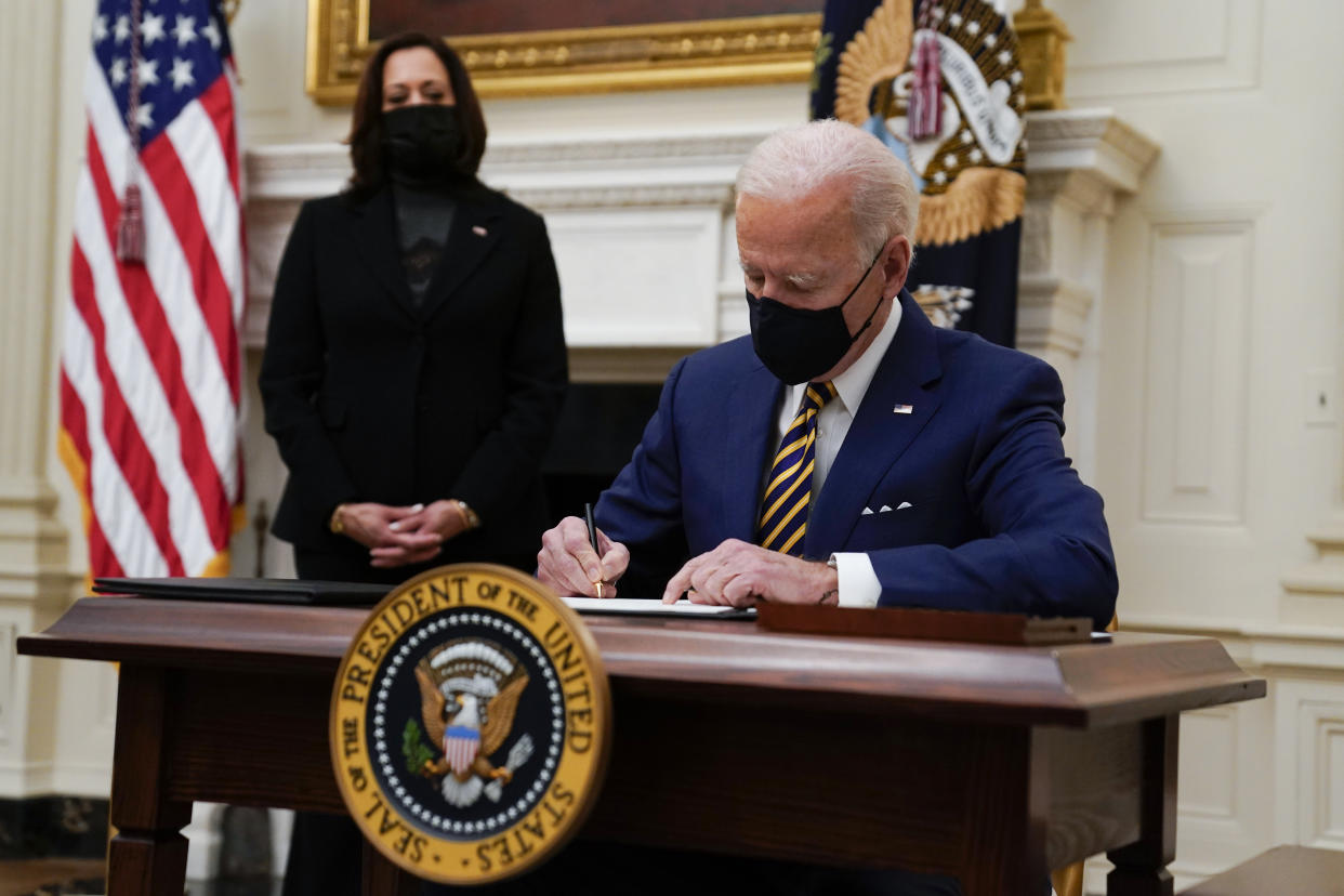 President Joe Biden signs executive orders on the economy in the State Dining Room of the White House, Friday, Jan. 22, 2021, in Washington. Vice President Kamala Harris looks on at left. (AP Photo/Evan Vucci)