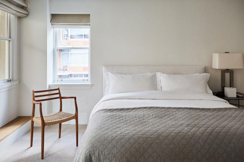 The guest room’s wooden chair adds a natural material to an otherwise simple and modern space. A slate gray coverlet provides a slightly urban edge.