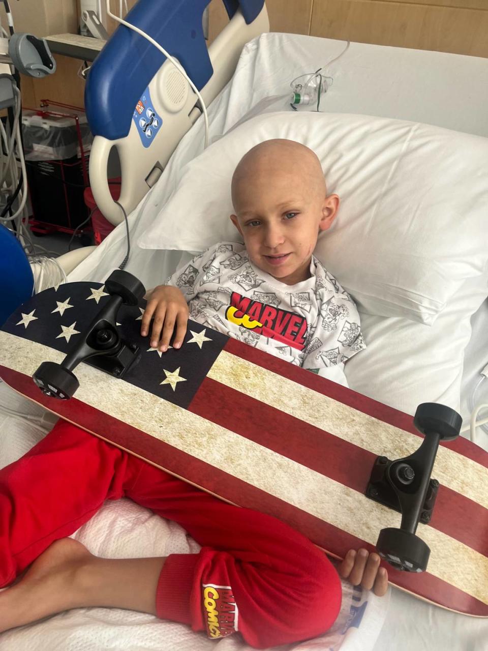 Logan Jenner, diagnosed with acute myeloid leukemia, holds a skateboard after receiving his third cancer treatment. His cancer came back in 2021.