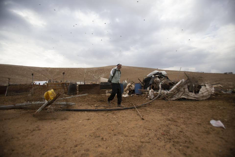 A Palestinian walks by destroyed tents in Khirbet Humsu in Jordan Valley in the West Bank, Friday, Nov. 6, 2020. Israeli troops with bulldozers and heavy equipment demolished 18 tents and other structures that housed 74 people, including 41 minors, according to the Israeli rights group B'Tselem. COGAT, the Israeli military body in charge of civilian affairs in the West Bank, said an "enforcement activity" was carried out against seven tents and eight pens that were "illegally constructed" in a firing range. (AP Photo/Majdi Mohammed)