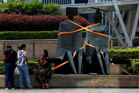 People rest beside a tightened up sculpture at the financial Central district as as Typhoon Mangkhut approaches Hong Kong, China September 15, 2018. REUTRERS/Bobby Yip