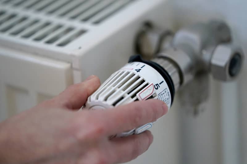 A woman turns a heating thermostat. Marcus Brandt/dpa