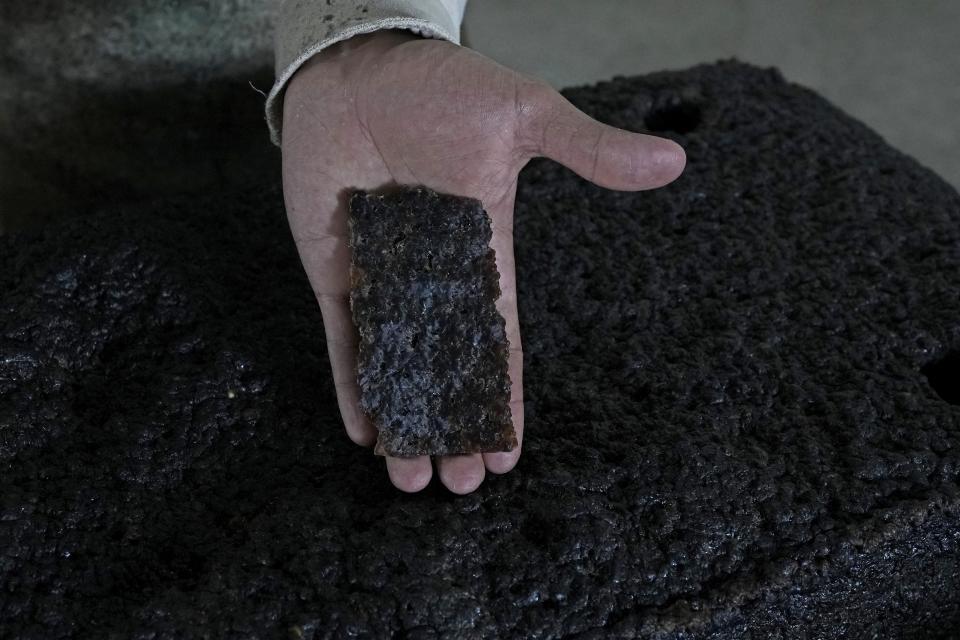 A worker shows a piece of a processed rubber plate taken for sample control at a rubber industrial plant of the cooperative called Cooperacre, in Sena Madureira, Acre state, Brazil, Friday, Dec. 9, 2022. The shoe manufacturer Veja works with Cooperacre, reenergizing the production of a sustainable forest product and improving the living of hundreds of rubber tapper families. (AP Photo/Eraldo Peres)