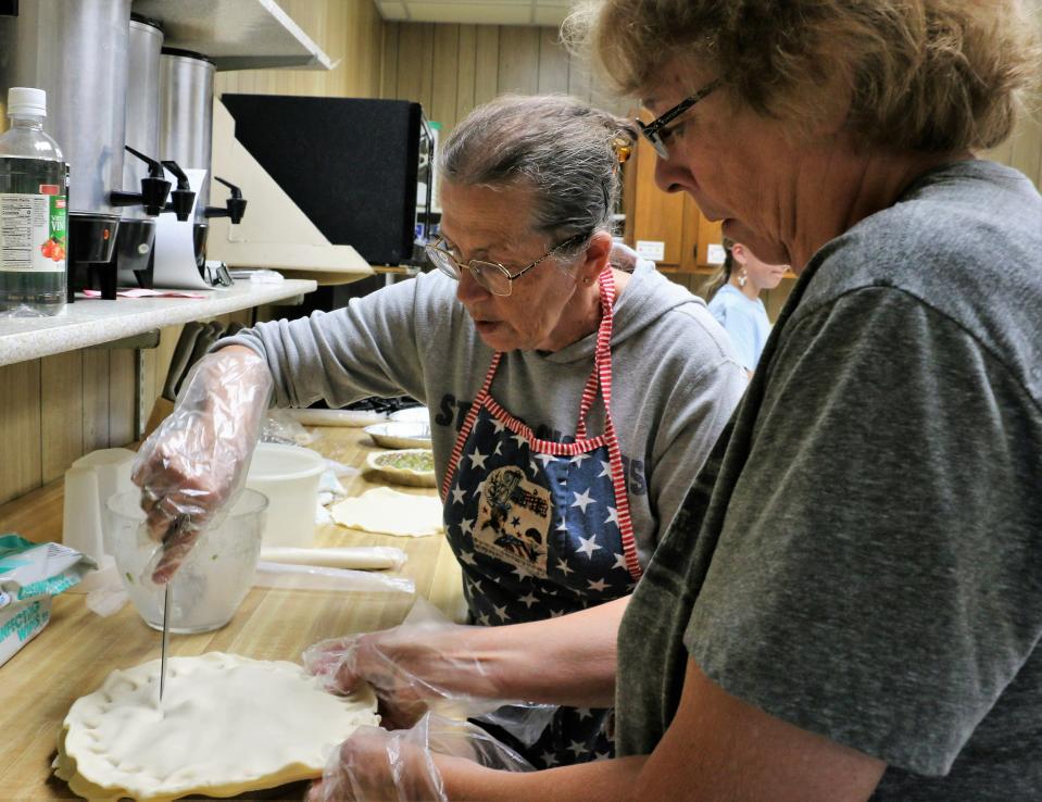 Deb Clark, left, cuts vent holes into the last batch of rhubarb pies made in Quimby. The town of 249 baked nearly 300 pies for RAGBRAI.