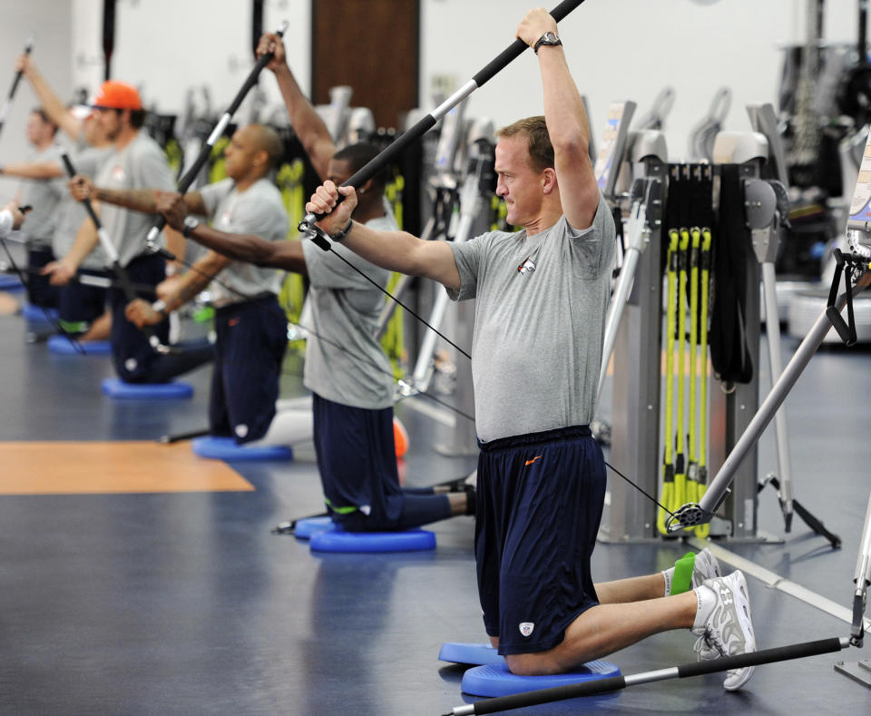 In this photo provided by the Denver Broncos, quarterback Peyton Manning, right, and other offensive players work during the first phase of the offseason training program at the NFL football teams training facility in Englewood, Colo., on Monday, April 21, 2014. (AP Photo/Denver Broncos, Eric Lars Bakke)