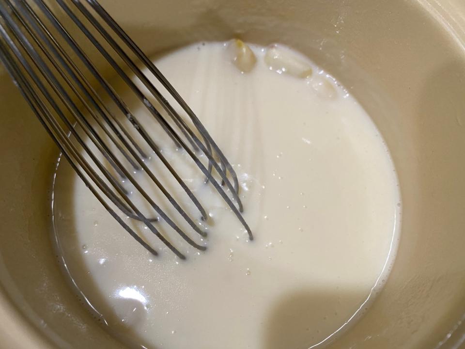 béchamel sauce cooking in a pot with a whisk