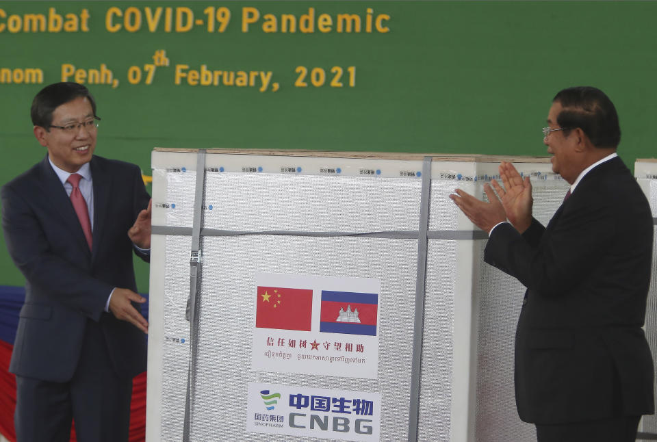 Chinese ambassador to Cambodia Wang Wentian, left, presents a box loaded with COVID-19 vaccines to Cambodian Prime Minister Hun Sen during a handover ceremony at Phnom Penh International Airport, in Phnom Penh, Cambodia, Sunday, Feb. 7, 2021. Cambodia on Sunday received its first shipment of COVID-19 vaccine, a donation of 600,000 doses from China, the country's biggest ally. Beijing has been making such donations to several Southeast Asian and African nations in what has been dubbed "vaccine diplomacy," aimed especially at poorer countries like Cambodia. (AP Photo/Heng Sinith)