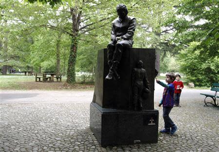 Children play next to the memorial statue of Formula One Brazilian driver Ayrton Senna in the park inside the race track at Imola April 22, 2014. REUTERS/Alessandro Garofalo