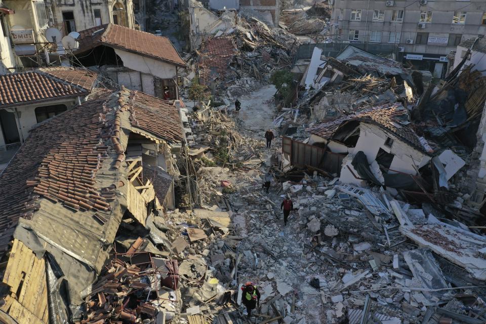 People walk among destroyed building in the old city of Antakya, southern Turkey, Monday, Feb. 13, 2023. Thousands left homeless by a massive earthquake that struck Turkey and Syria a week ago packed into crowded tents or lined up in the streets for hot meals Monday, while the desperate search for anyone still alive likely entered its last hours. (AP Photo/Hussein Malla)