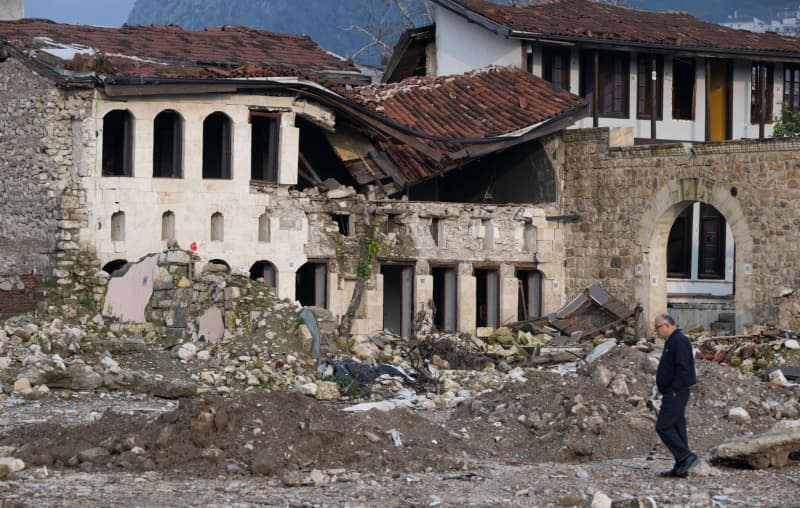 A man walks past destroyed houses in the old town of Antakya. Numerous houses in the city center were destroyed or severely damaged in the quake a year ago. Boris Roessler/dpa