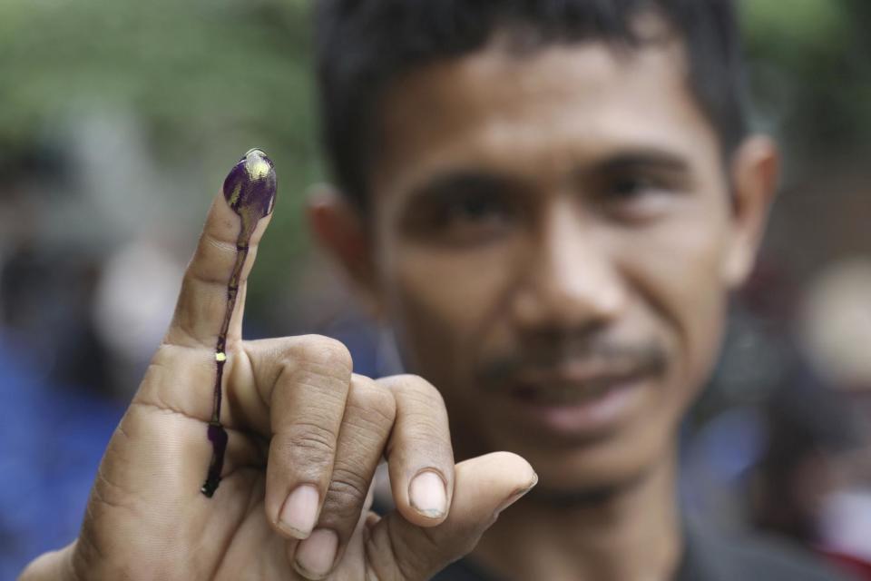 An Indonesian man shows his ink-stained finger after voting in Jakarta, Indonesia, Wednesday, Feb. 15, 2017. Voting began in the election for governor of the Indonesian capital after a months-long campaign in which the monumental problems facing Jakarta took a backseat to religious intolerance and racial bigotry. (AP Photo/Achmad Ibrahim)