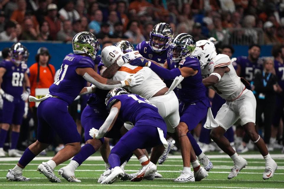 Texas tight end Ja’Tavion Sanders (0) is tackled by the Washington defense during the Alamo Bowl at the Alamodome, Thursday, Dec. 29, 2022 in San Antonio.