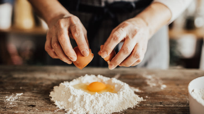 man adding egg to flour