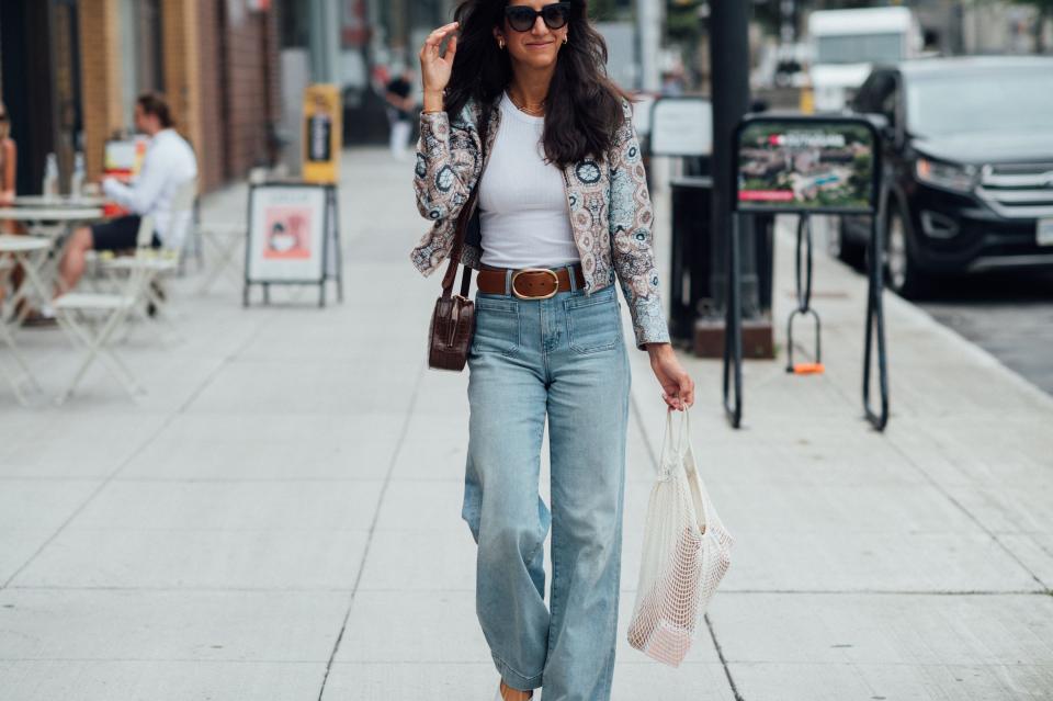Alyssa Beltempo walking on a sidewalk wearing jeans and a patterned jacket