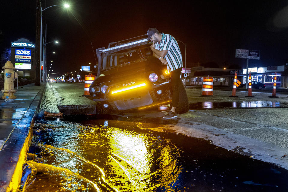 El conductor Miguel Reyes se sienta sobre su vehículo, el cual cayó en un hoyo en medio de una inundación en el Charleston Boulevard, el jueves 28 de julio de 2022, en Las Vegas. (L.E. Baskow/Las Vegas Review-Journal vía AP)