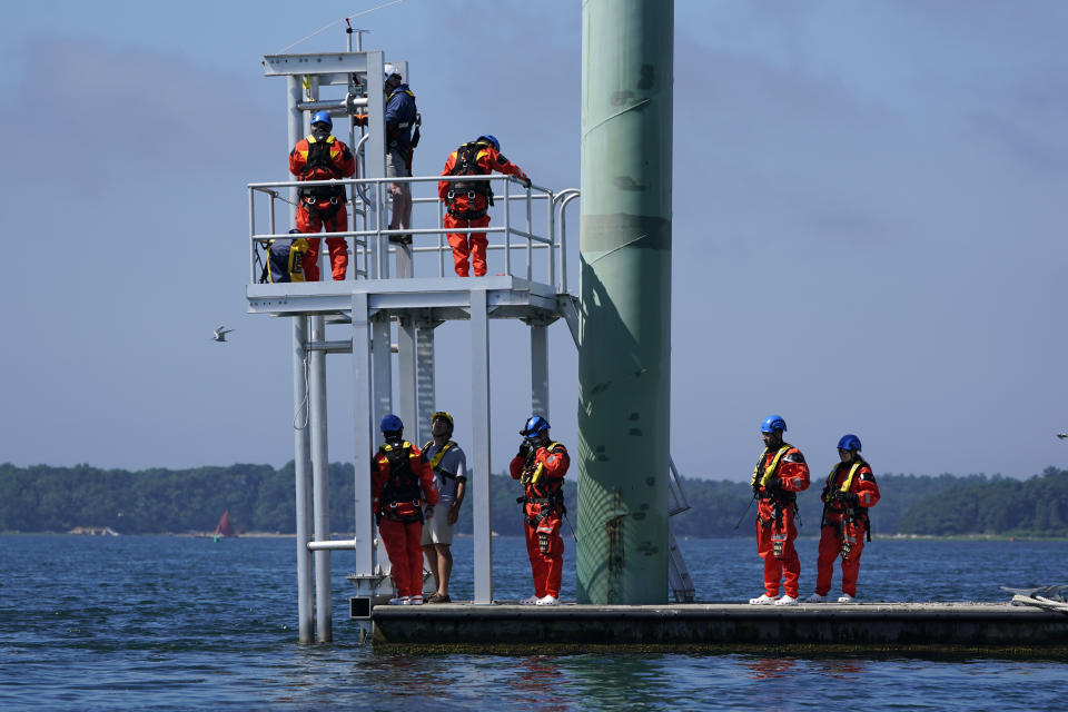 Participants, wearing waterproof suits, learn evacuation techniques that might be used in an emergency situation on an off shore wind turbine during a Global Wind Organisation certification class at the Massachusetts Maritime Academy in Bourne, Mass., Thursday, Aug. 4, 2022. At the 131-year-old maritime academy along Buzzards Bay, people who will build the nation's first commercial-scale offshore wind farm are learning the skills to stay safe while working around turbines at sea. (AP Photo/Seth Wenig)