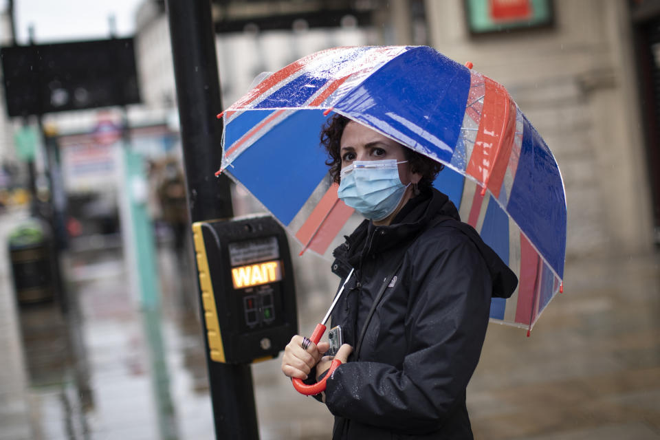 LONDON, ENGLAND - OCTOBER 13: A woman walks near Piccadilly Circus wearing a face mask on October 13, 2020 in London, England. London Mayor Sadiq Khan said today that the city would move into Tier 2 of the government's new covid-19 risk classification once it hits 100 new daily cases per 100,000 people, which could happen this week. The second or "high" tier of the three-tier system triggers a ban on household mixing, although pubs would remain open. (Photo by Dan Kitwood/Getty Images)