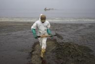 A worker, dressed in a protective suit, cleans Conchitas Beach contaminated by an oil spill, in Ancon, Peru, Thursday, Jan. 20, 2022. The oil spill on the Peruvian coast was caused by the waves from an eruption of an undersea volcano in the South Pacific nation of Tonga. (AP Photo/Martin Mejia)