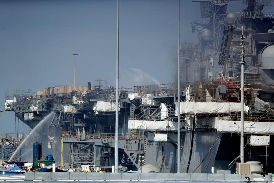 FILE - Fire crews spray water from the dock onto the side of the USS Bonhomme Richard, in San Diego, July 12, 2020 (AP)