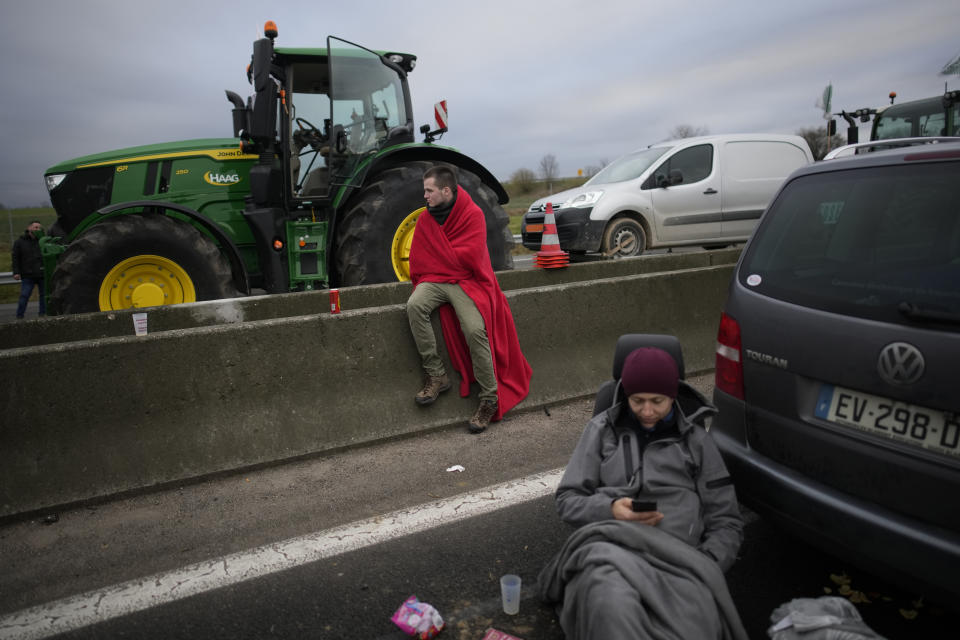 Farmers relax as farmers block a highway Tuesday, Jan. 30, 2024 in Jossigny, east of Paris. With protesting farmers camped out at barricades around Paris, France's government hoped to calm their anger with more concessions Tuesday to their complaints that growing and rearing food has become too difficult and not sufficiently lucrative. (AP Photo/Christophe Ena)