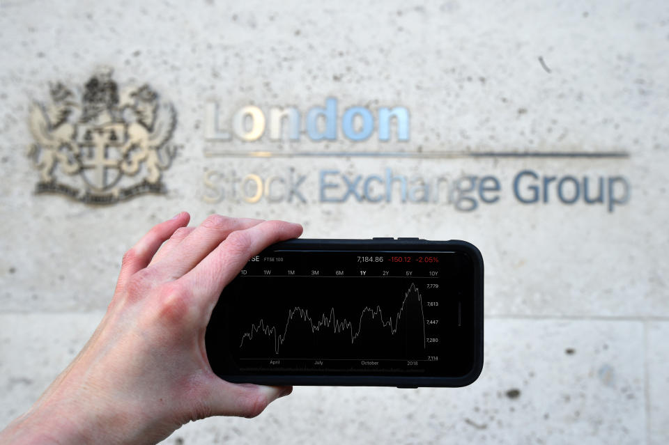 FTSE 100 A view of the Stocks app on an iPhone against the London Stock Exchange sign in the City of London, as the FTSE 100 Index crashed on opening by more than 230 points to 7,104.94 as inflation fears continue to rock global markets.