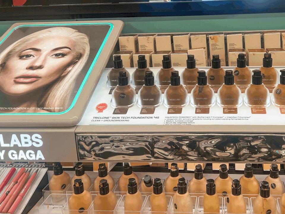 Display of circular-shaped bottles of Haus Labs foundation at Sephora. A graphic of Lady Gaga sits next to the foundation