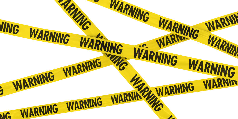 Yellow police tape is criss-crossed across the image, with the word warning printed repeatedly on it.