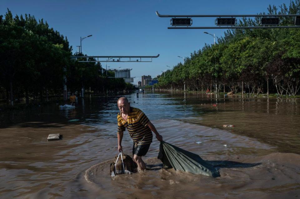 A man pulls a bag full of goods salvaged from a building as he wades through receding floodwaters on August 5, 2023 in Zhuozhou, Hebei Province south of Beijing, China.