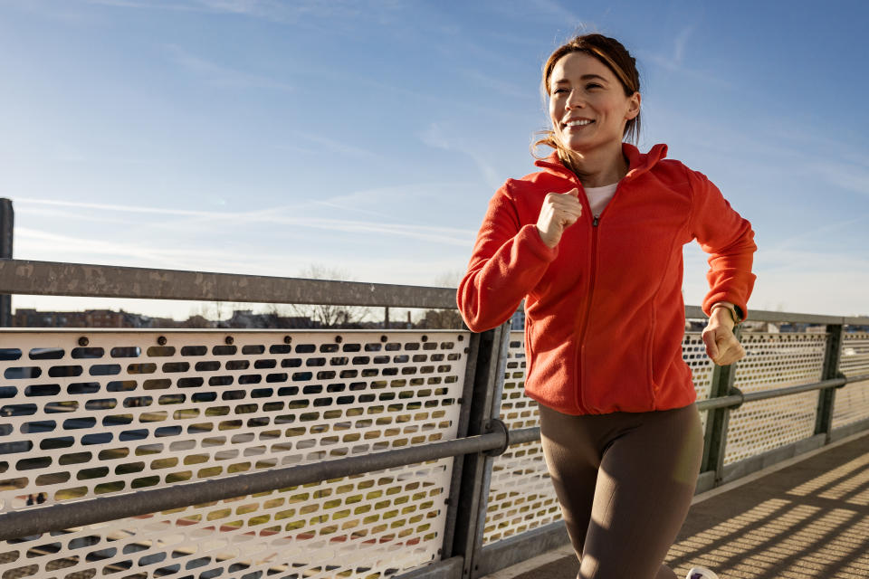 Happy sportswoman jogging at the bridge