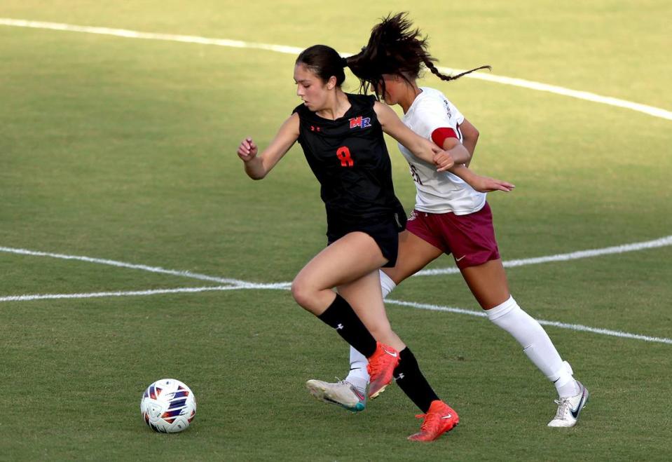 Marvin Ridge’s Lucy Chin, left, pushes the ball downfield against a Wilmington Ashley defender during first half action of the NCHSAA 4A state final game at the Matthews Sportsplex in Matthews, NC on Friday, May 31, 2024.