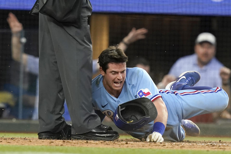 Texas Rangers' Nick Solak, front right, slides into the home plate umpire after scoring from third base on a bunt by teammate Charlie Culberson during the third inning of a baseball game against the Atlanta Braves in Arlington, Texas, Sunday, May 1, 2022. (AP Photo/LM Otero)