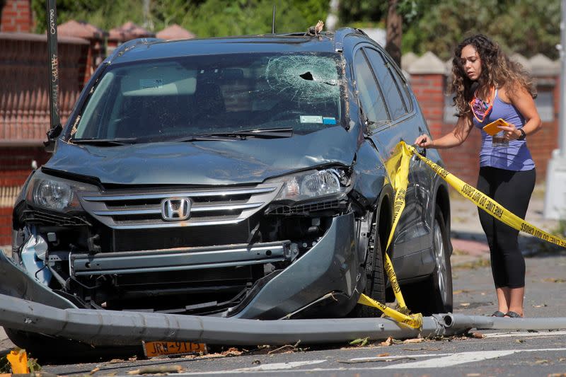 The owner of a damaged car examines it the aftermath of Tropical Storm Isaias in the Astoria neighborhood of Queens, New York