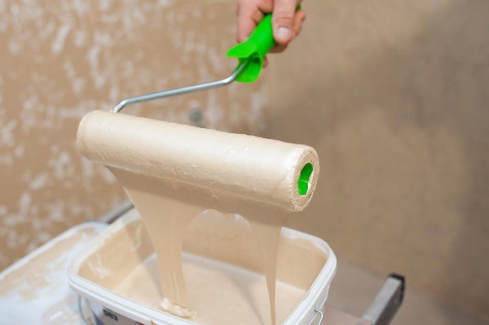 a paint roller covered in paint dripping from the bottom