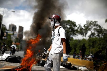 A demonstrator stands in front of a barricade during a strike called to protest against Venezuelan President Nicolas Maduro's government in Caracas. REUTERS/Carlos Garcia Rawlins