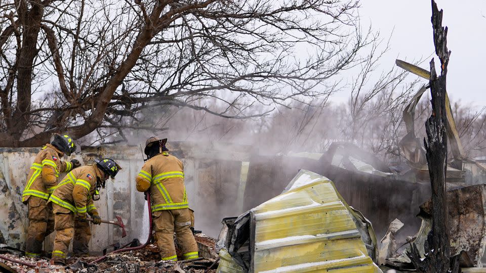 Firefighters from Lubbock, Texas, help put out the smoldering debris of a home destroyed by the Smokehouse Creek Fire on Thursday in Stinnett, Texas. - Julio Cortez/AP
