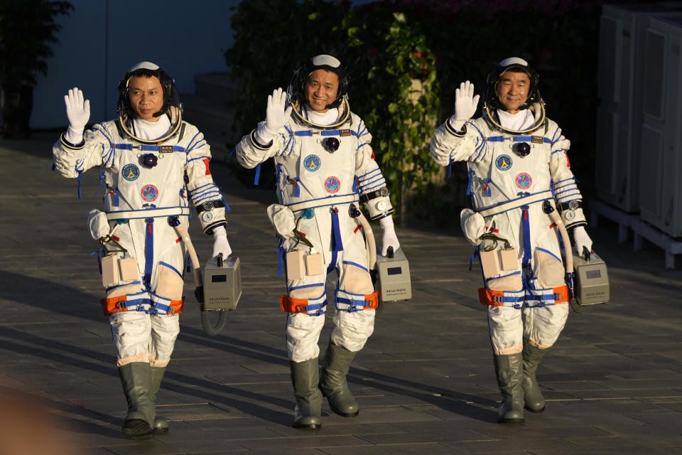 Chinese astronauts, from left, Tang Hongbo, Nie Haisheng and Liu Boming wave as they prepare to board for liftoff at the Jiuquan Satellite Launch Center in Jiuquan in northwestern China, on Thursday, June 17, 2021. / Credit: Ng Han Guan / AP