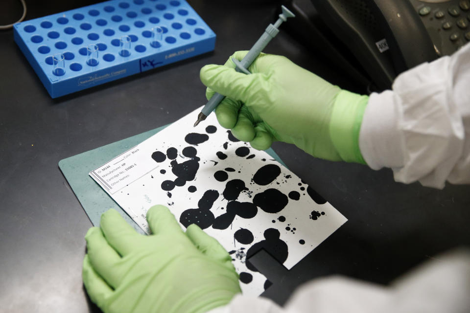 In this June 27, 2019 photo, document analysis technician Irvin Rivera collects samples of inkjet printer ink in the International Ink Library at the U.S. Secret Service headquarters building in Washington. The library was recently dedicated to Antonio Cantu, a renowned investigator and former chief chemist at the Secret Service who started picking up samples decades ago. (AP Photo/Patrick Semansky)