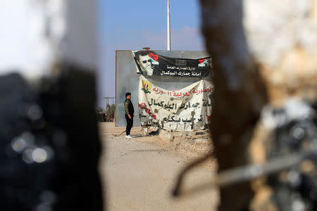 A banner depicting Syrian President Bashar al-Assad is seen on the Syrian side of the border with Iraq through the al-Qaim gate on the Iraqi side, November 26, 2018. REUTERS/Alaa al-Marjani