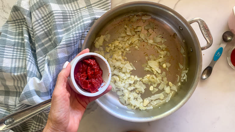 adding tomato paste to pan