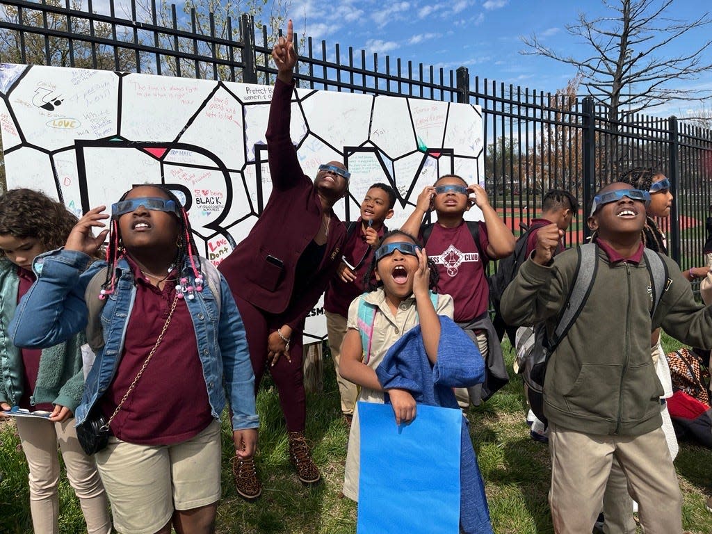 Tiffany Johnson, principal of Whittier Elementary School in Washington, D.C., points toward the sun while talking to excited students.