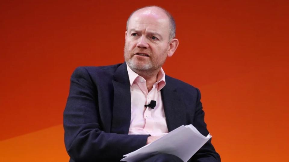 New CNN boss Mark Thompson wearing a black jacket and pink shirt, speaking onstage at a conference.