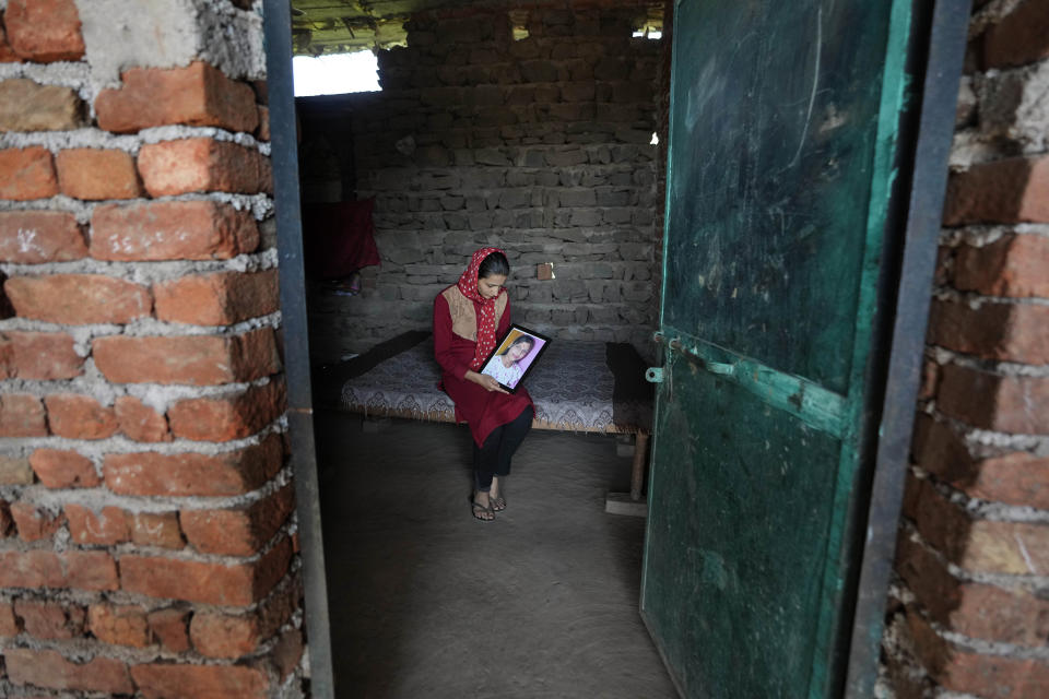 A relative holds the photograph of Samiksha Sharma who was killed in an attack on Hindus at Dhangri Village, in Rajouri, India, Feb. 7, 2023.Days after seven Hindus were killed in the village in disputed Kashmir, Indian authorities revived a government-sponsored militia and began rearming and training villagers. The militia, officially called the “Village Defense Group,” was initially formed in the 1990s as the first line of defense against anti-India insurgents in remote villages that government forces could not reach quickly. (AP Photo/Channi Anand)