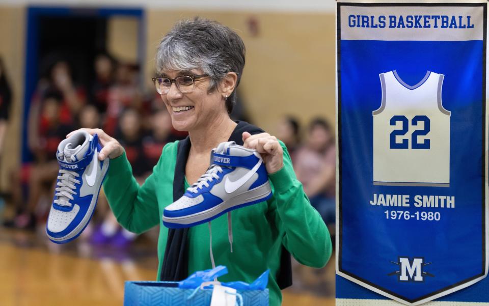 Former McCallum High School girls basketball star Jamie Smith displays a pair of gifted basketball shoes during the school's jersey retirement ceremony in her honor recently. At the event, she was recognized for her outstanding achievements in girls sports.