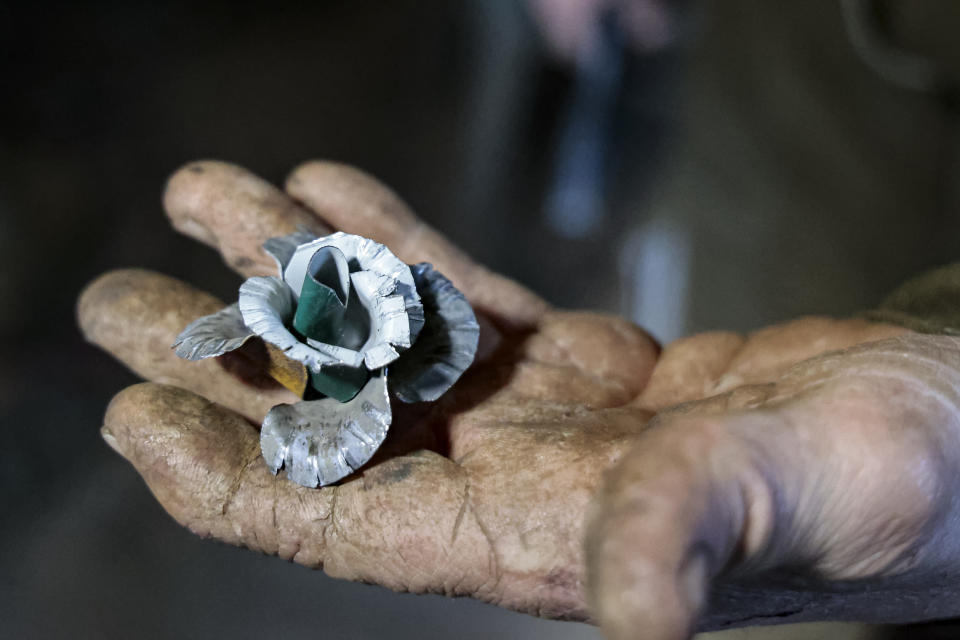 Viktor Mikhalev shows a rose transformed from weapons and ammunition into flowers of war in a workshop in his house in Donetsk, Russian-controlled Donetsk region, eastern Ukraine, Saturday, March 4, 2023. Mikhalev, trained as a welder, lives and works in a house whose fence and door are decorated with forged flowers and grapes. (AP Photo/Alexei Alexandrov)