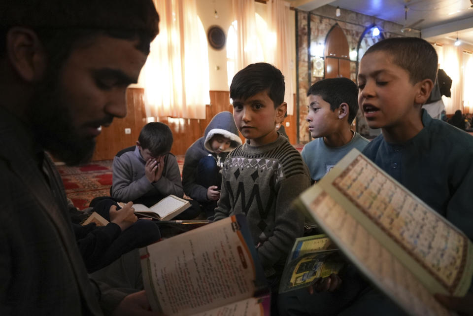 Sanam, a bacha posh -- a girl living as a boy, center, sits among Afghan boys as they read the Quran, Islam's holy book, during a class at a mosque, in Kabul, Afghanistan, Wednesday, Dec. 8, 2021. In the heavily patriarchal, male-dominated society of Afghanistan, where women and girls are usually relegated to the home, there is one tradition which allows girls access to the male world: Bacha posh. A girl dresses, behaves and is treated as a boy, allowing her to play and to work as a boy would be able to do. (AP Photo/Mstyslav Chernov)