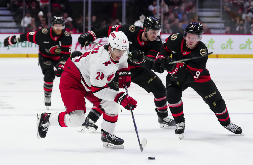 Carolina Hurricanes center Seth Jarvis (24) skates the puck towards the net and Ottawa Senators center Josh Norris (9) skates towards him during the first period of an NHL hockey match in Ottawa, Ontario, on Tuesday, Dec. 12, 2023. (Sean Kilpatrick/The Canadian Press via AP)